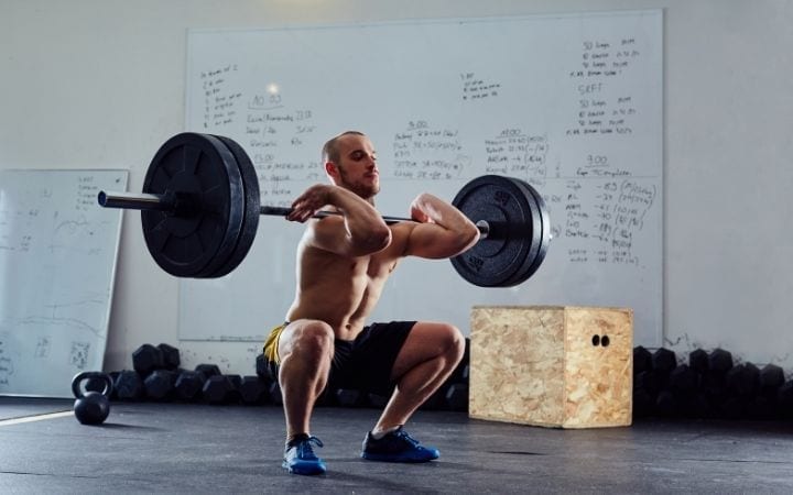 Man doing front squat with barbell in gym | Jiu Jitsu Legacy
