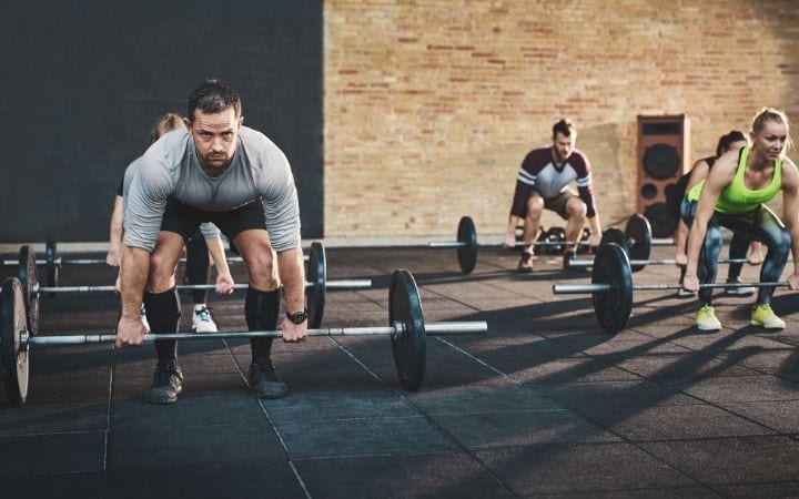 Group strength training, doing dead lifts with barbells